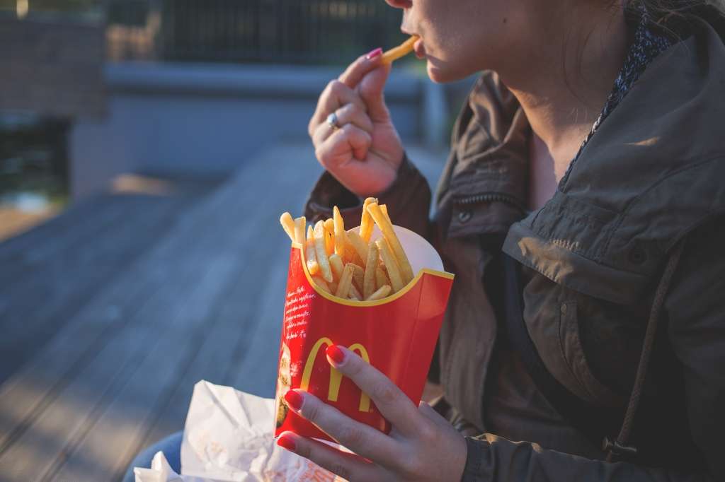 Canva - Woman in Brown Classic Trench Coat Eating Mcdo Fries during Daytime.jpg
